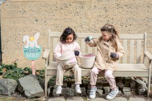 content multiracial girls playing with easter eggs on bench