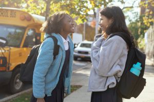 joyful diverse schoolgirls chatting and laughing on street